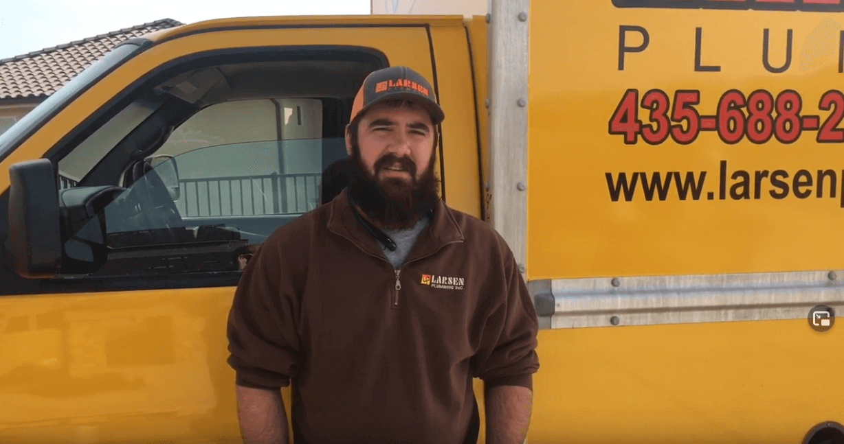Plumber standing in front of yellow van, discussing Best Lubricant for Plumbers, Wrenches and Tools.