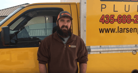 Plumber standing in front of yellow van, discussing Best Lubricant for Plumbers, Wrenches and Tools.