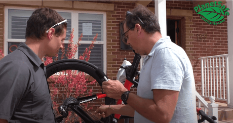 Two people discussing bike maintenance with PlanetSafe AiM in front of a house. World's Best Bike Lube - How AiM Lube Lubricates Your Bike Properly.
