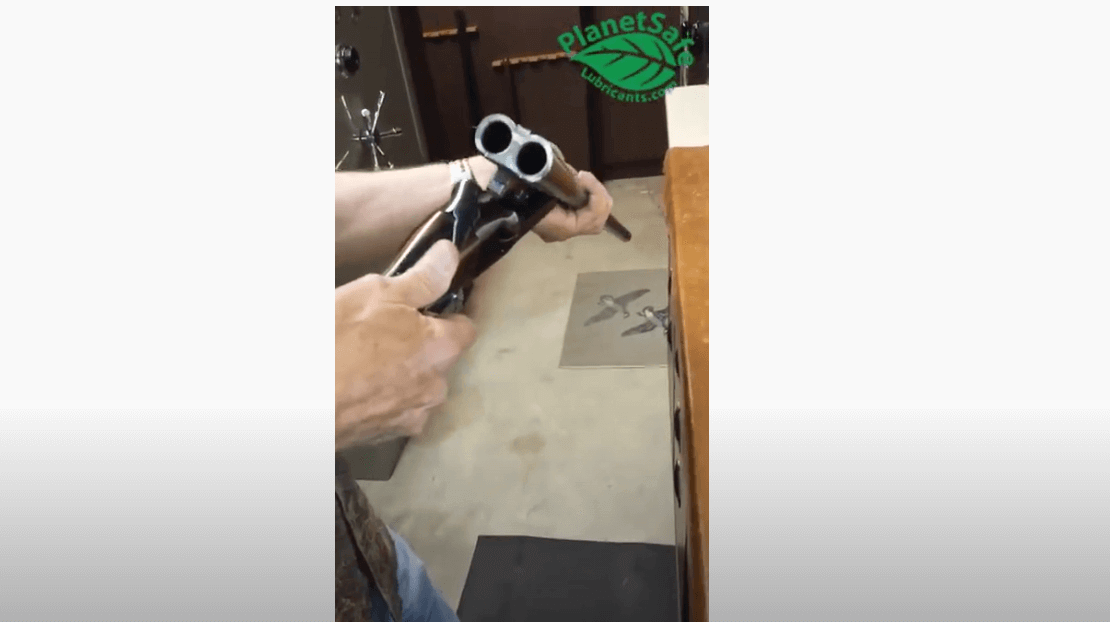 Applying Best Gun Lube - AIM Lube on a shotgun in a gunsmith's workshop, highlighting its effectiveness as a firearms lubricant and cleaner.