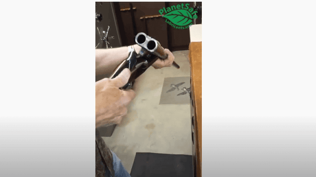 Applying Best Gun Lube - AIM Lube on a shotgun in a gunsmith's workshop, highlighting its effectiveness as a firearms lubricant and cleaner.