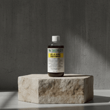 Bottle of oil and gear treatment on a stone block with a gray background